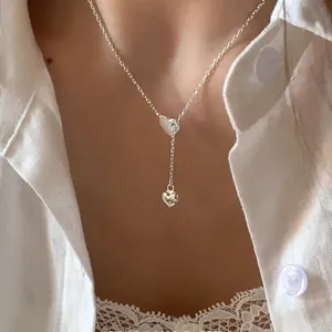 Elegant silver heart pendant Y-necklace worn by a model on a minimalist white shirt