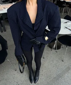 Detail of pinstripe blazer featuring exaggerated wide shoulders and waist-cinching design