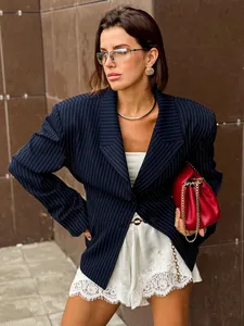 Close-up detail of a navy pinstripe blazer paired with a red quilted chain shoulder bag