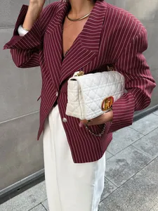 Detail of white quilted leather bag with gold CD buckle paired with striped blazer