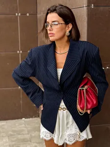 Detail of pinstripe blazer with chic gold chain belt and a stylish red leather handbag