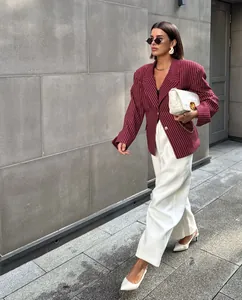 Detailed street shot of a burgundy pinstripe blazer paired with white wide-leg trousers