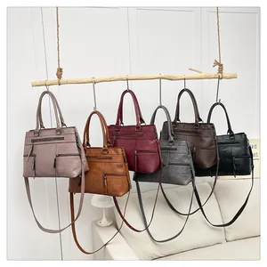 Multi-pocket leather crossbody handbags hanging on a wood branch in six colors