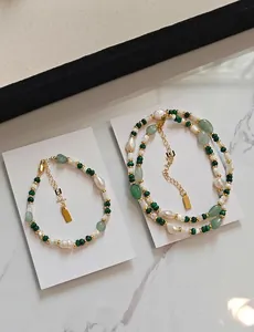 Detail of aventurine and freshwater pearl necklace with golden clasp on marble
