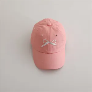 Détail d'une casquette rose en coton avec broderie de nœud blanc et œillets d'aération
