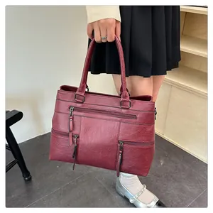 Detail of burgundy faux leather tote bag with multi-zipper pockets and dual handles