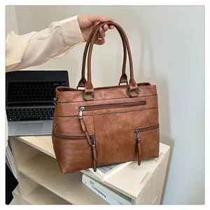 Close-up of vintage brown leather tote with multi-zipper pockets and dual handles