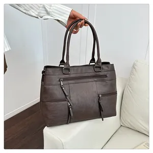 Detail view of coffee brown tote bag showing smooth faux leather texture and multi-pocket design