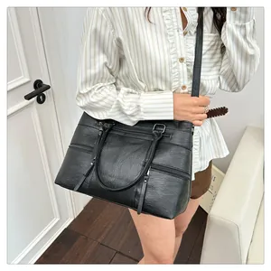 Detailed view of black leather tote bag with functional zippers and dual top handles