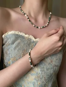 Detail of baroque pearl and green malachite beaded necklace set on a female model