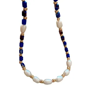 Lapis lazuli and freshwater pearl necklace with golden beads on white background