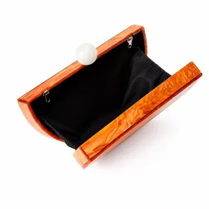 Detail view of acrylic evening bag with amber marble texture and pearl clasp closure