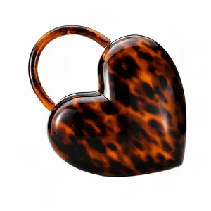 Detail of heart-shaped acrylic evening bag with vintage tortoiseshell texture and round handle