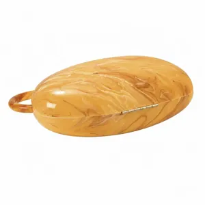Detail of amber tortoiseshell acrylic clutch showing golden hinge and round handle