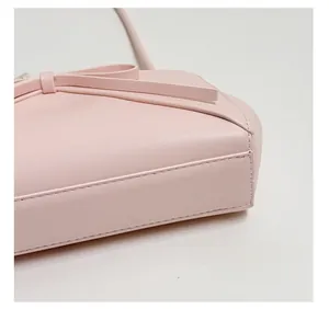 Détail du sac en cuir rose montrant le fond renforcé et la décoration de nœud