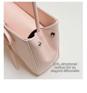 Détail du sac à main rose en cuir texturé montrant le bouton pression et les coutures