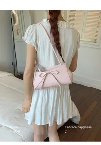 Gros plan d'un sac sous le bras en cuir rose clair avec un nœud décoratif élégant