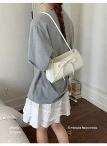 Détail d'un sac à bandoulière blanc avec un grand nœud et des lanières fines