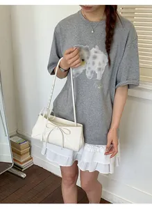 Détail du sac à main en cuir blanc crème avec nœud élégant et foulard en soie à pois