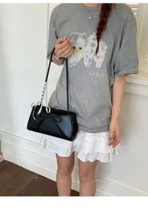 Détail du sac bandoulière en cuir mat noir avec nœud tissé et foulard en soie à pois