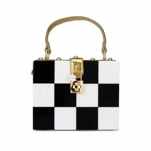 Detail view of checkerboard box bag with golden handle and white flower charm lock