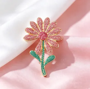 Close-up of luxury daisy brooch with pink crystals and gold-plated floral detailing