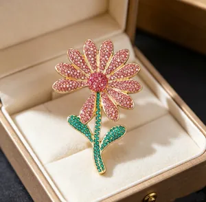 Macro shot of luxury pink crystal daisy brooch with green leaf detail in a jewelry box