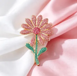 Macro shot of luxury daisy brooch with pink and red crystals on silk background