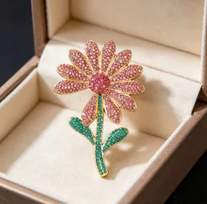 Close-up of a luxury daisy brooch featuring pink and green rhinestones on gold alloy