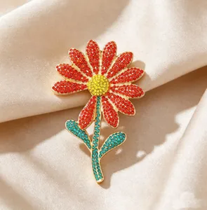 Detailed view of luxury daisy flower brooch with red and yellow rhinestones on silk