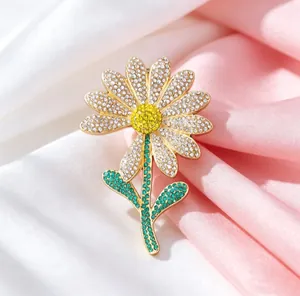 Detailed view of luxury daisy brooch with white petals and green crystal leaves on silk