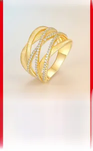 Macro detail of gold-plated brushed metal texture and pavé moissanite setting on the ring