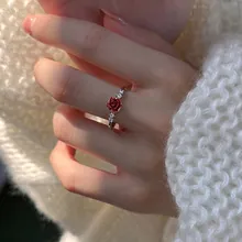 Detail of red rose ring with small side diamonds on silver band worn by a model