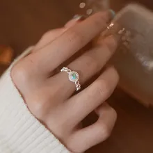 Detail of a silver twisted ring featuring a blue-green opal surrounded by small crystals