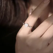 Detailed view of square cut sparkling stone ring on finger with soft warm lighting