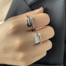 Detailed view of silver guitar shaped open ring worn on hand with black enamel finish