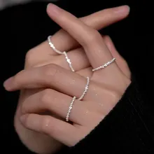 Detail of silver layered rings with textured finish and zircon star accents on hand
