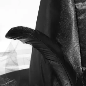 Detail of a black witch hat with shiny silver glitter finish and elegant feather accent