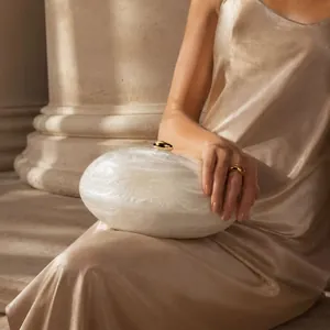 Détail de la pochette en nacre blanche avec fermoir doré et style de soirée élégant