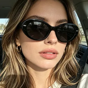 Women's vintage oval sunglasses in black finish worn by a model in a car setting
