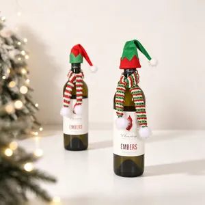 Close-up of mini knitted Christmas hats and scarves set on wine bottles for table decor