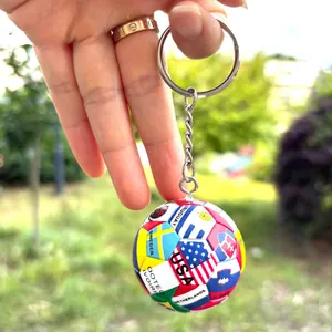 Fußball-Schlüsselanhänger mit Weltflaggen und Metallring in der Hand im Freien