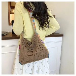 Close-up of a handmade crochet shoulder bag with colorful floral strap and hollow weave