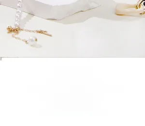 Macro detail of summer style pearl necklace featuring a gold toggle clasp and metal chain