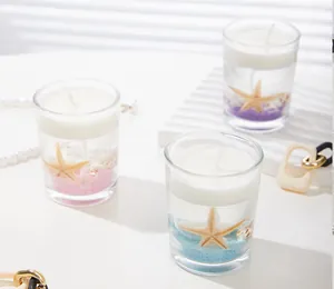 Detail of ocean-themed jelly candle with seashells and colored sand in glass jar