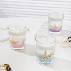 Ocean themed jelly candles with seashells and starfish in glass jars on a bright desk