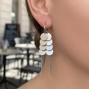Gros plan de boucles d'oreilles à disques argentés polis avec franges sur mannequin