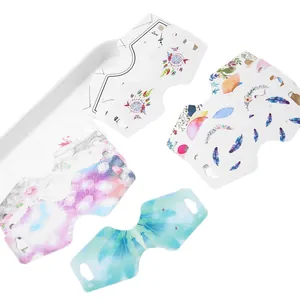 Various jewelry packaging display cards with dreamcatcher and marble patterns on white tray