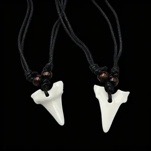 Détail de deux pendentifs dent de requin sur cordons tressés noirs avec perles en bois