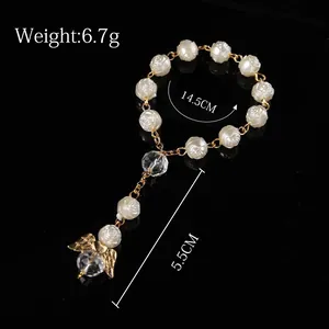 Detailed view of religious pearl bracelet with rose beads and golden angel wing charm